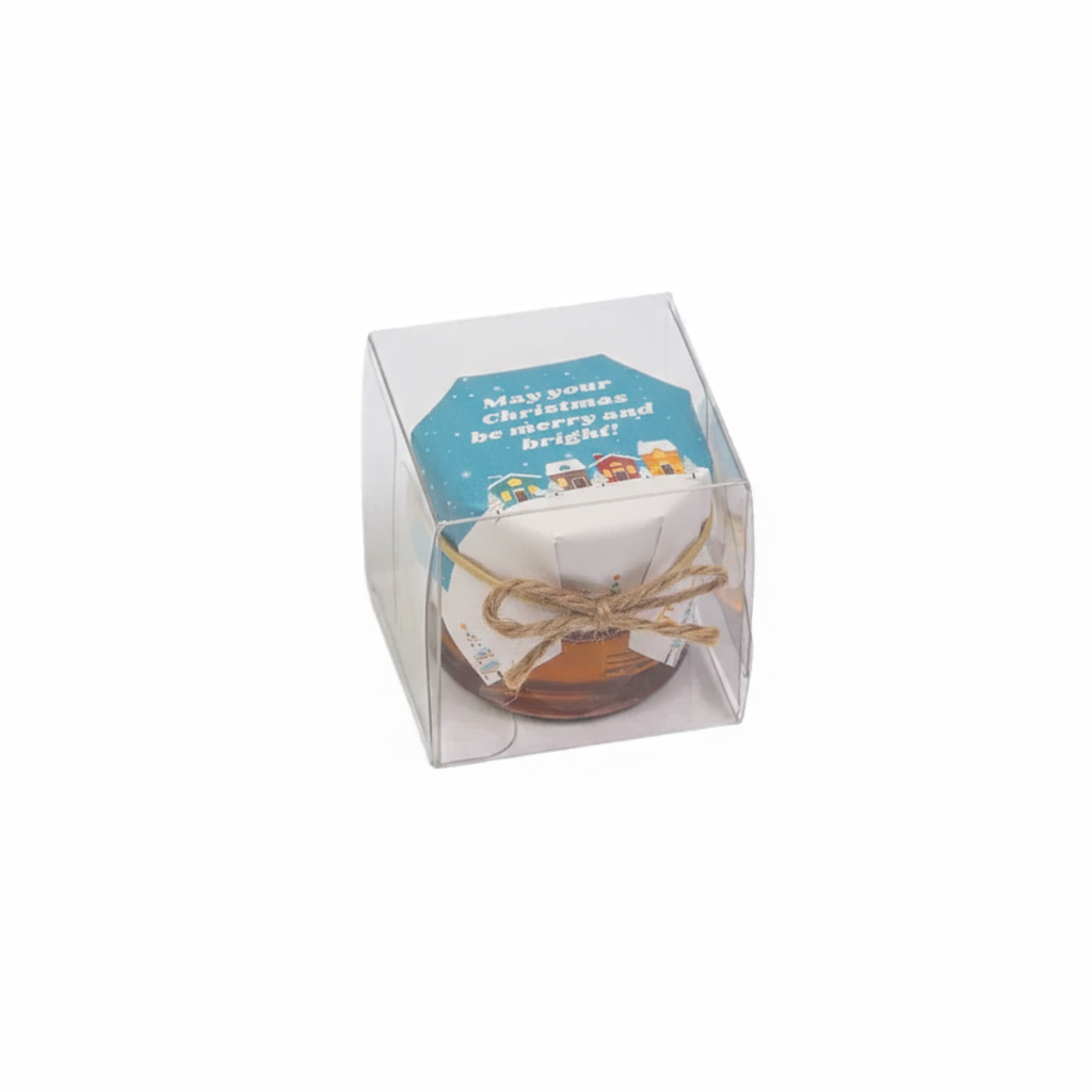 Clear gift box with a Christmas-themed card and small item inside on a white background