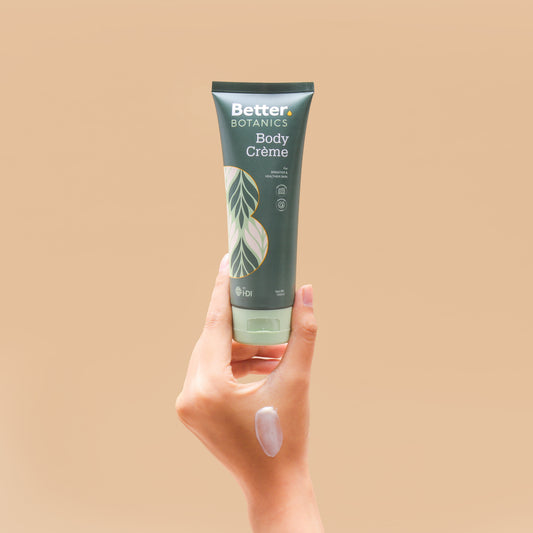 Hand holding a tube of Better Botanics Body Creme against a beige background