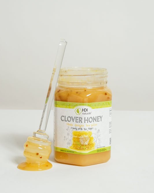Jar of clover honey with a honey dipper on a white background