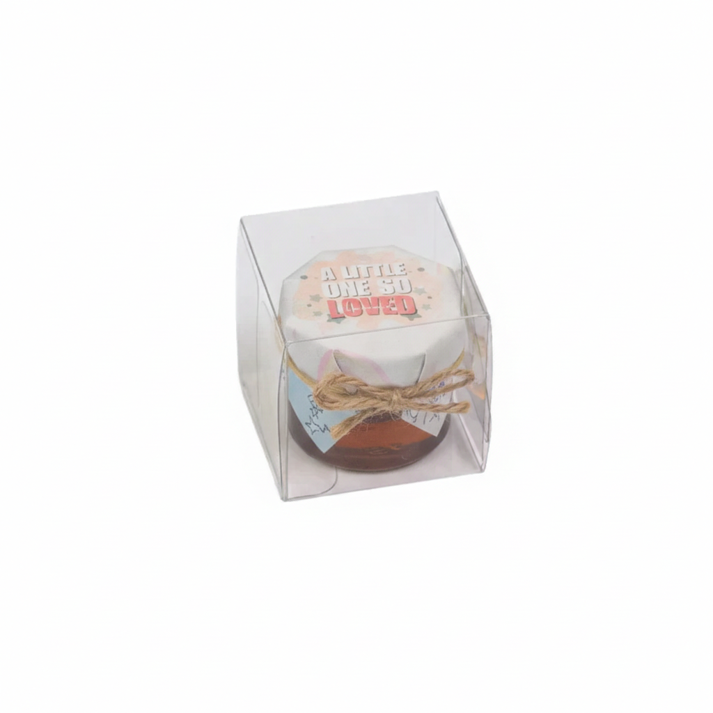 Small jar with a label reading 'A Little One So Loved' in a clear box on a white background