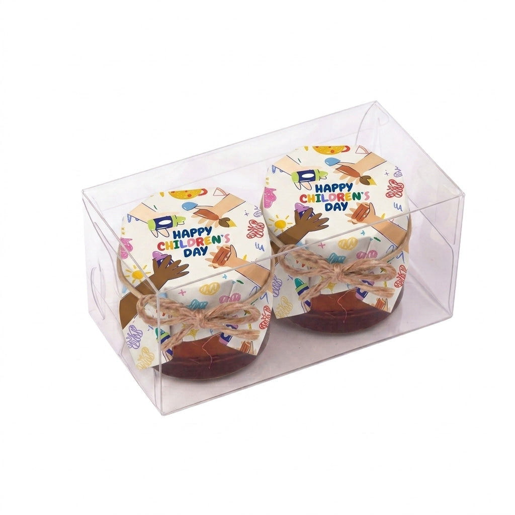 Small honey jar gift in a transparent clear box, wrapped in colorful Happy Children's Day packaging with a twine bow.