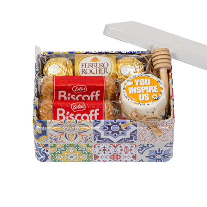 Colorful gift tin with Ferrero Rocher chocolates, Lotus Biscoff cookies, a honey jar, and a honey dipper.
