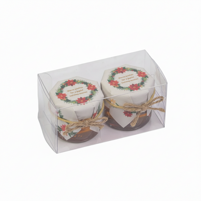 Two small jars with decorative labels in a clear packaging box on a white background