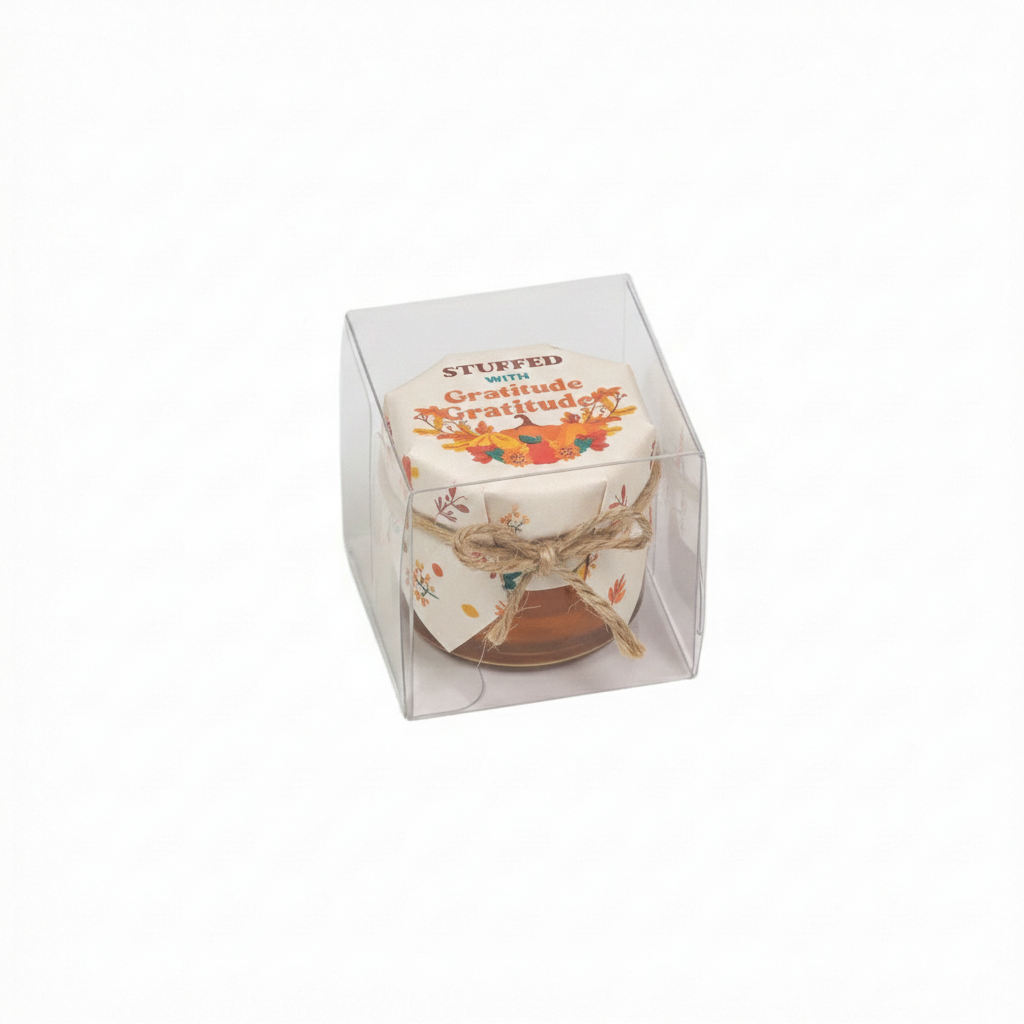 Small container with decorative lid in a clear packaging box on a white background