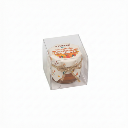 Small container with decorative lid in a clear packaging box on a white background