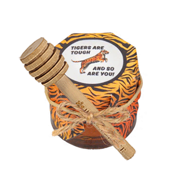 Honey container with tiger pattern and wooden dipper on a white background