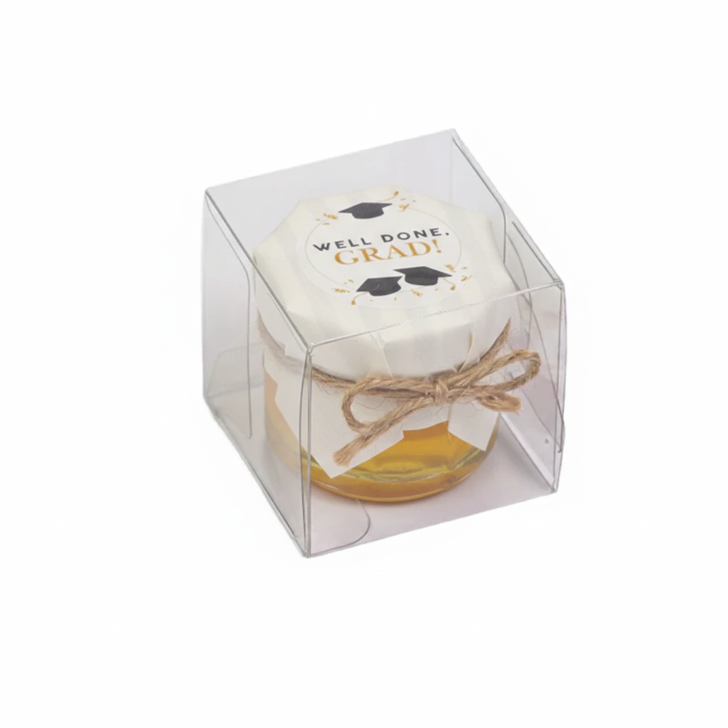 Jar of honey with a decorative label in a clear cube packaging on a white background