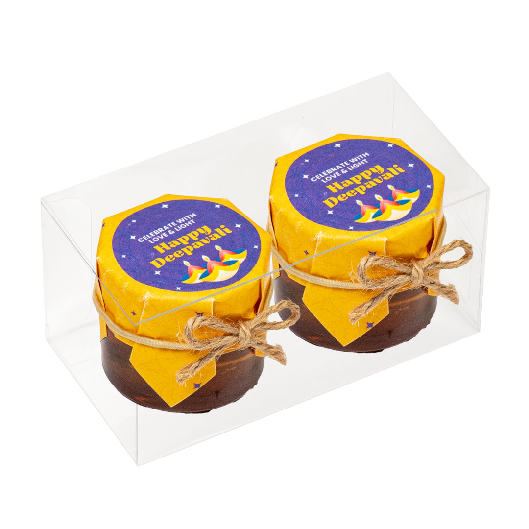 Two small jars with 'Happy Diwali' labels in a clear box on a white background